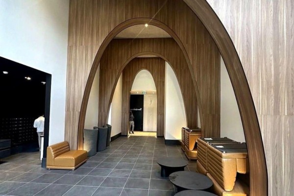Building lobby with curved wooden arches, tiled floor, and contemporary seating. - 525 - 270 Dufferin Street S, Toronto