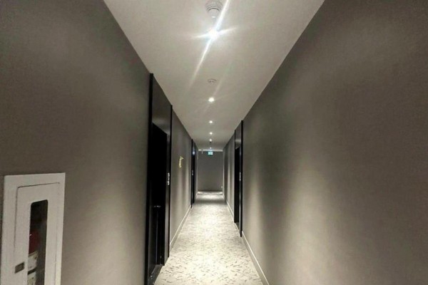 Long, dimly lit hallway with grey walls, carpet, and recessed lighting. - 525 - 270 Dufferin Street S, Toronto