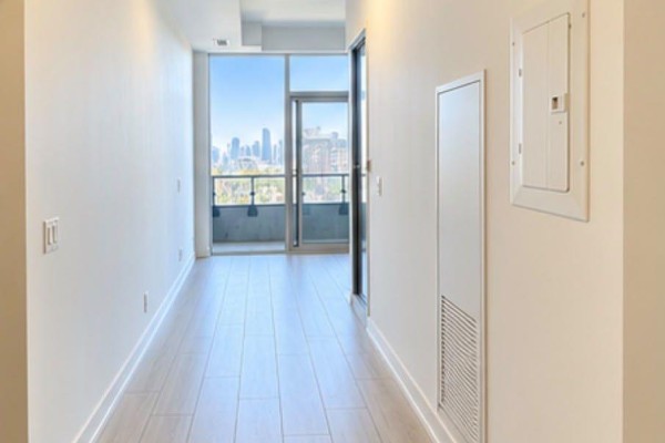 Hallway with light wood floors leading to a balcony with city view. - 525 - 270 Dufferin Street S, Toronto