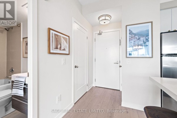 Hallway leading to entrance with bathroom on left and kitchen island on right. - 525 - 8 Fieldway Road, Toronto