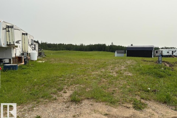 Grassy land with RVs and a new construction site, trees in background. - #525 454029 Rge Road 11, Rural Wetaskiwin County