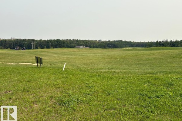 Expansive green golf course landscape with a distant building and utility poles. - #525 454029 Rge Road 11, Rural Wetaskiwin County