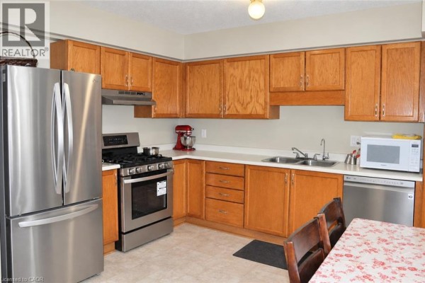 Kitchen with light oak cabinets, stainless steel refrigerator, gas stove, dishwasher, and light beige tiled floor. - 525 Oakvale Drive Unit# 2, Waterloo
