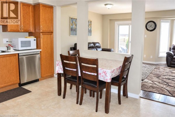 Open concept kitchen and dining area with dark wood chairs and a patterned tablecloth, opening to a living room. - 525 Oakvale Drive Unit# 2, Waterloo