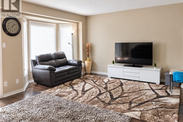 Living room with a dark brown leather loveseat, bay windows with white blinds, and a large area rug. - 525 Oakvale Drive Unit# 2, Waterloo