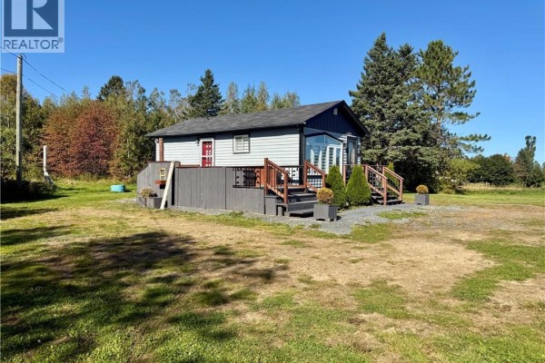 Rear exterior of the bungalow with grey vinyl siding and dark grey fencing. - 525 Route 135, Hacheyville