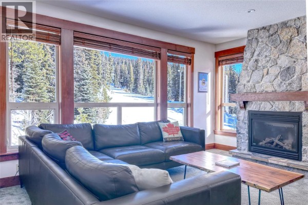 Skiers on a groomed slope with chairlifts and evergreen trees. - 5257 Big White Road Unit# 306, Big White