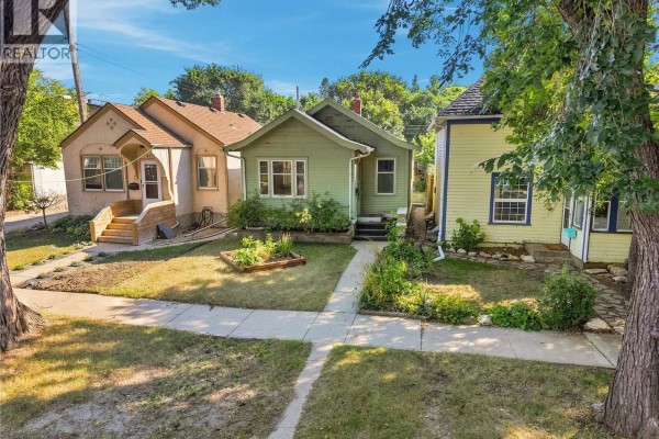 Aerial view of a light green house on a tree-lined street with surrounding homes. - 526 7th Street E, Saskatoon