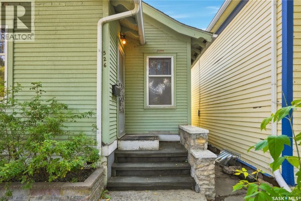 Close-up of the entrance to a light green house with stone steps and pillars. - 526 7th Street E, Saskatoon