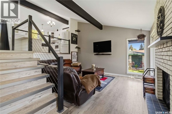 Living room with a sectional leather sofa, a coffee table, and a large window overlooking the yard. - 526 Tobin Crescent, Saskatoon