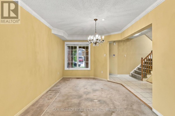 Empty dining room with beige carpet, yellow walls, and a chandelier. - 5263 Russell View Road, Mississauga