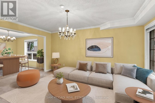 Living room with a sectional sofa, coffee table, dining area in background, and yellow walls. - 5263 Russell View Road, Mississauga