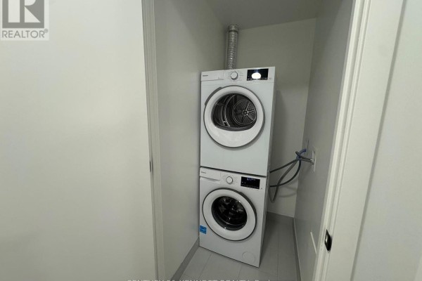 Stacked white washer and dryer in a compact laundry closet with a vent. - 527 - 91 Montclair Avenue, Toronto