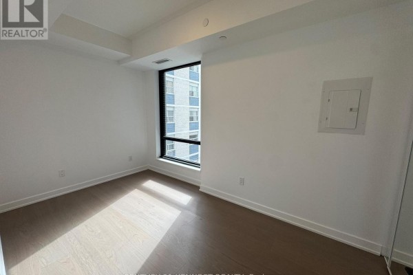 Empty bedroom with hardwood floors, white walls, and a large window. - 527 - 91 Montclair Avenue, Toronto