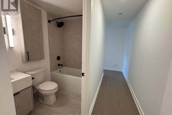 Small bathroom with toilet, bathtub, and vanity, adjacent to a hallway. - 527 - 91 Montclair Avenue, Toronto