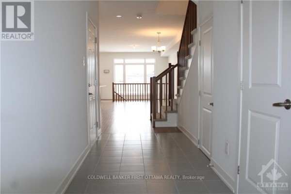 Tiled entryway with hardwood floors leading to a staircase and living area. - 527 Corretto Place, Ottawa