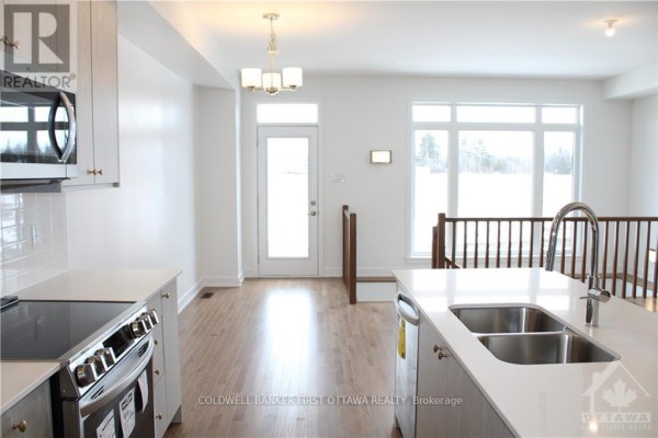 View from kitchen to dining area, door to outside, large windows, and staircase. - 527 Corretto Place, Ottawa