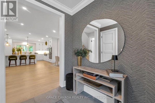 View from the entryway into an open-concept living space with a kitchen island and light wood flooring. - 527 Oneida Drive, Burlington