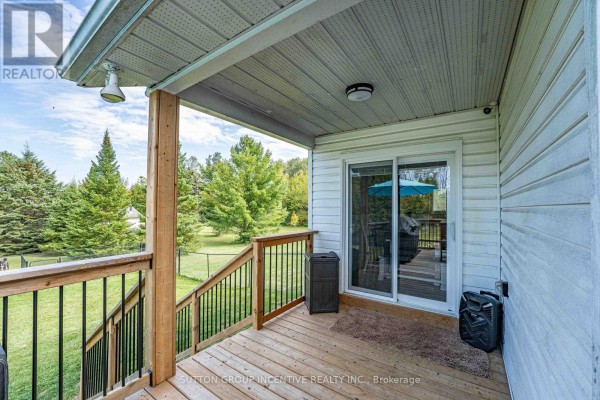 Covered front porch with a bench, pillows, welcome sign, and glass door. - 5274 5 Sunnidale Concession Road, Clearview