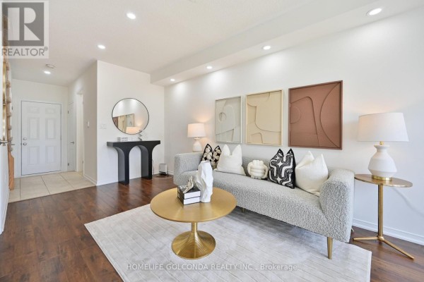 Living room with a sofa, coffee table, mirrors, and artwork on white walls. - 5277 Major Mackenzie Drive E, Markham