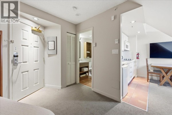 Apartment entrance with white doors, hallway with access to bathroom and kitchenette area. - 528 4295 Blackcomb Way, Whistler