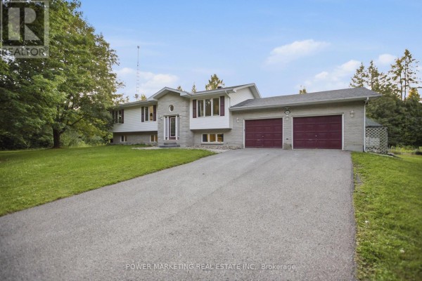 Exterior view of the raised bungalow from the driveway, showcasing a large green lawn and mature trees. - 528 Kings Creek Road, Beckwith