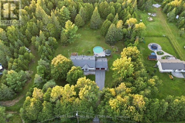 Overhead drone shot of the property surrounded by dense green trees, featuring a raised bungalow and pool. - 528 Kings Creek Road, Beckwith