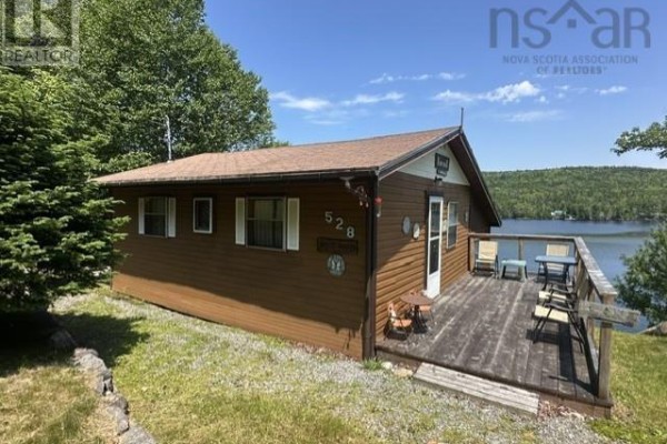 Small brown cottage with white trim and a wooden deck with seating. Lake view. - 528 West Side Indian Harbour Lake Road, Indian Harbour Lake