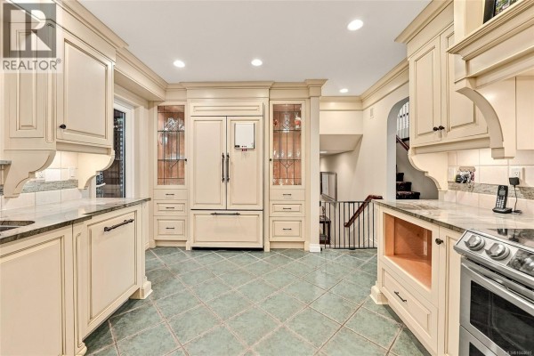 Cream-colored kitchen with stainless steel appliances, tile floor, and built-in cabinetry. - 5287 Lost Lake Rd, Nanaimo