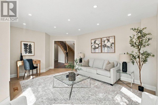 Living room with a grey sofa, glass coffee table, desk, and a view of the staircase. - 5289 Fallingbrook Drive, Mississauga