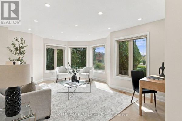 Living room with a bay window, two white armchairs, and a desk area. - 5289 Fallingbrook Drive, Mississauga