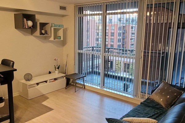 Living room with a sofa, vertical blinds, and sliding glass doors opening to a balcony. - 529 - 830 Lawrence Avenue W, Toronto