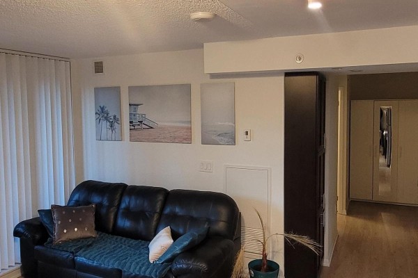 Interior view showing a sofa, wall art, and hallway entrance with mirrored closet doors. - 529 - 830 Lawrence Avenue W, Toronto