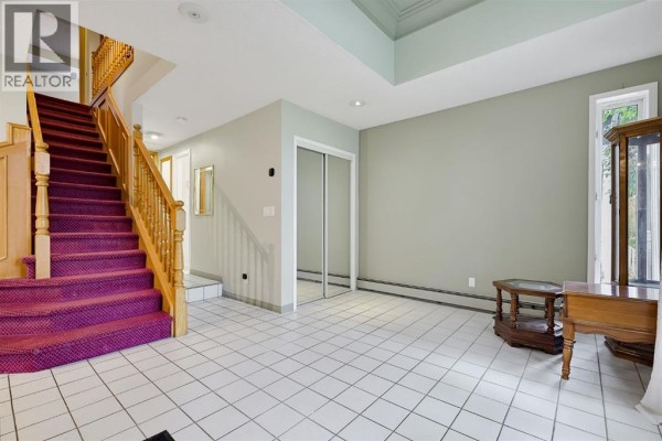 Foyer with white tiled floor, a carpeted staircase, mirrored closet doors, and a tall window. - 529 18 Avenue Nw, Calgary