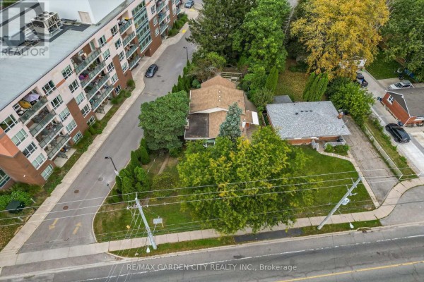 Aerial view of a bungalow with a modern apartment building behind it. - 529 Carlton Street, St  Catharines