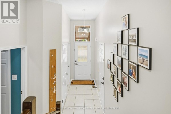 Hallway view from above showing a tiled floor, white walls, and framed photos. - 529 St Lawrence Drive, Welland