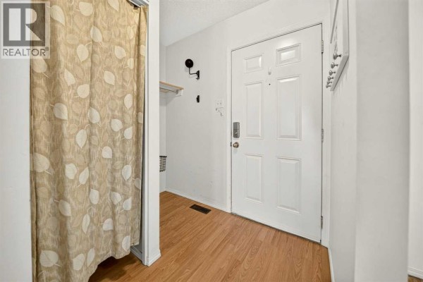 Interior entryway with a white front door, wood laminate flooring, and a patterned shower curtain. - 53, 55 Lemoyne Crescent W, Lethbridge