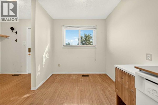 Dining area with a window overlooking trees, wood laminate flooring, and light beige walls. - 53, 55 Lemoyne Crescent W, Lethbridge