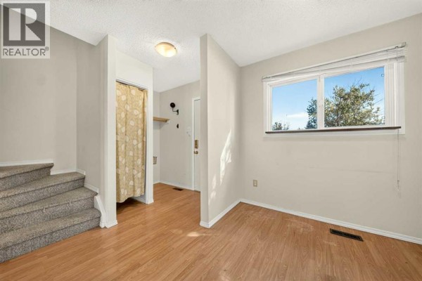 Room with a window, wood laminate flooring, and a view of trees and sky. - 53, 55 Lemoyne Crescent W, Lethbridge