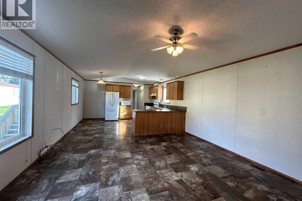 Living room with a ceiling fan, sofa, and open view to the kitchen. - 53, 6205 54 Street, Ponoka