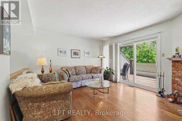 Living room with hardwood floors, floral sofas, glass coffee table, and deck access. - 53 - 110 Havelock Street, Ottawa