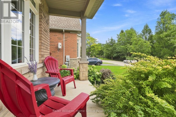 Front porch with red chairs, a small table, and lush green landscaping. - 53 - 145 Aberfoyle Mill Crescent, Puslinch