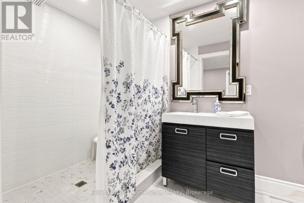 Modern bathroom with dark vanity, ornate mirror, floral shower curtain, and textured tile - 53 - 145 Aberfoyle Mill Crescent Puslinch