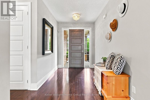 Interior entryway with dark hardwood floors, a grey door, and decorative hats on wall. - 53 - 145 Aberfoyle Mill Crescent, Puslinch