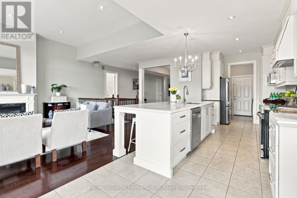 Modern kitchen with island, stainless steel appliances, and fireplace in living area - 53 - 145 Aberfoyle Mill Crescent Puslinch