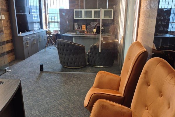View into an office with tufted chairs, desk, and cabinetry through glass walls. - 53 - 2455 Cawthra Street, Mississauga