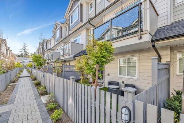 A paved pathway runs alongside fenced backyards of townhouses with balconies. - 53 13898 64 Avenue, Surrey