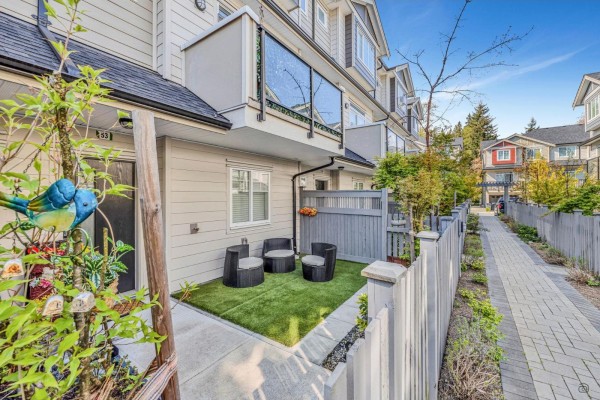 A small private patio with two chairs sits next to a townhouse entrance. - 53 13898 64 Avenue, Surrey