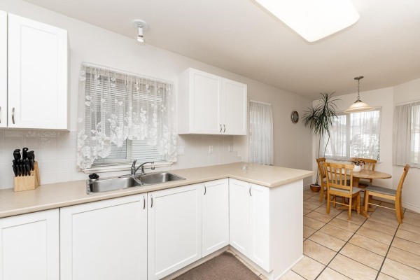 Dining area with a round wooden table, four chairs, and tiled flooring near a doorway. - 53 17516 4 Avenue, Surrey