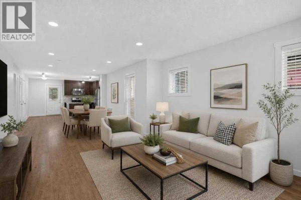 Living room with white sofa, chairs, coffee table, and dining area view. - 53 Cranford Way Se, Calgary
